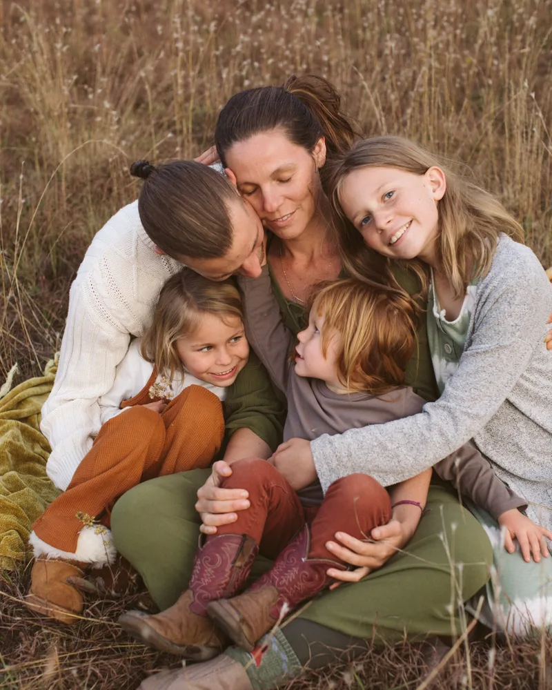 The Freedom Family: Matteo and Katt Lilly with their three children, sitting together in tall grass